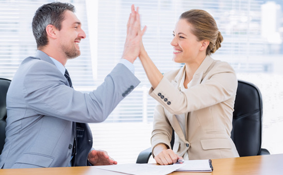  A business woman and a business man giving each other a high five.